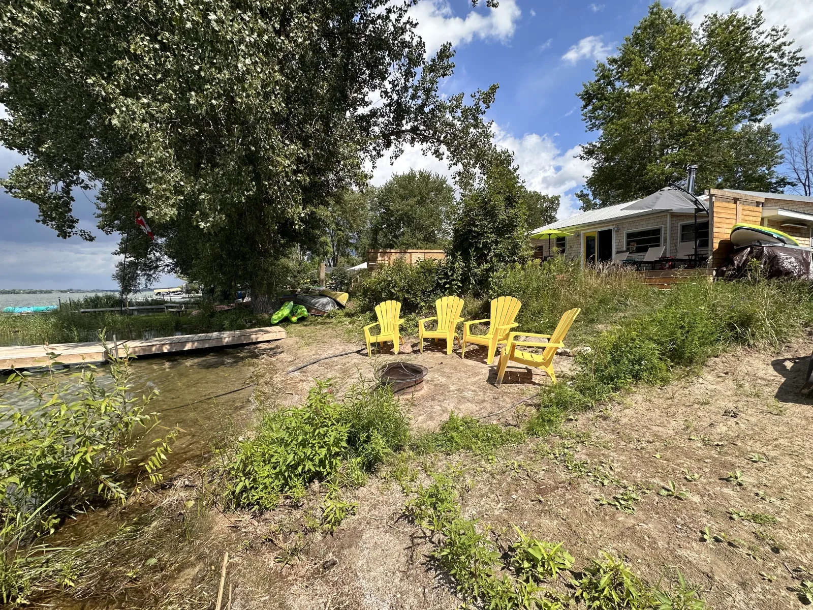 Walleye Cove waterfront with yellow chairs, fire pit, dock, and cottage
